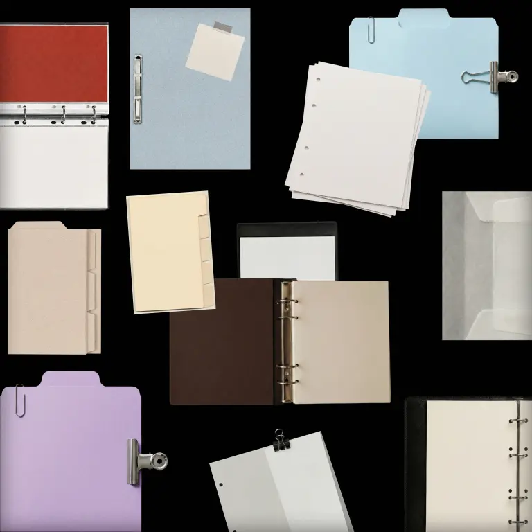Folders, binders and loose pages arranged on black.